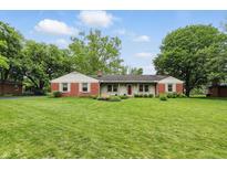 Charming single-story home with a manicured lawn and a combination of brick and light-colored siding at 5129 E 69Th St, Indianapolis, IN 46220