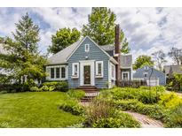 Charming blue bungalow with a brick chimney, garden landscaping, and walkway leading to the front entrance at 5219 N New Jersey St, Indianapolis, IN 46220