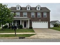 Brick two-story home with attached two car garage, green lawn, and mature shade tree at 6836 Eagle Crossing Blvd, Brownsburg, IN 46112