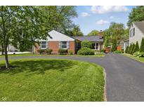 Charming brick home with a well-manicured lawn and a long, curved driveway at 7060 N Park Ave, Indianapolis, IN 46220