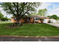 Charming brick home with a lush green lawn and mature trees, perfect for outdoor enjoyment at 76 Manhattan Ave, Indianapolis, IN 46241