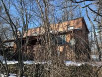 Cozy home with wood siding, complemented by bare winter trees, and a quaint front porch, set amongst an aged stone foundation at 8803 S Sleepy Hollow Rd, Waldron, IN 46182
