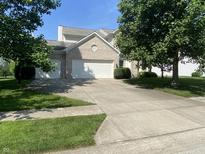 Beautiful brick home featuring a three-car garage and well-manicured lawn and driveway on a sunny day at 11727 Wedgeport Ln, Fishers, IN 46037