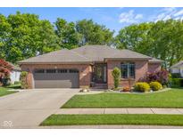 Charming single-story brick home featuring a two-car garage and meticulously landscaped front yard at 3781 S Station Dr, Columbus, IN 47203