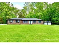 Charming brick home with a lush green lawn, mature trees, and a detached two-car garage at 504 W Gold Creek Rd, Mooresville, IN 46158