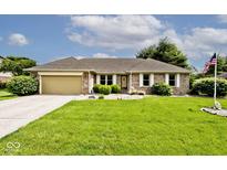 Charming brick home with a well-manicured lawn, an attached garage, and an American flag at 551 Windward Ln, Plainfield, IN 46168