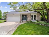 Charming ranch-style home with brick facade, attached garage, and mature landscaping at 7345 Monon Cir, Indianapolis, IN 46256