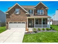 Charming two-story brick home featuring an attached garage and covered front porch at 8644 N Deer Crossing Blvd, McCordsville, IN 46055