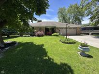 Charming ranch home featuring a well-manicured lawn, brick facade and an attached two car garage at 9521 Gemini Dr, Indianapolis, IN 46229