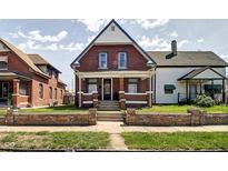Charming two-story brick home featuring a quaint front porch and well-maintained lawn at 1867 Barth Ave, Indianapolis, IN 46203