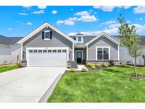 Charming home with a two-car garage, gray siding, stone accents, and a well-manicured lawn on a beautiful day at 19725 Highclere Lane, Sheridan, IN 46069