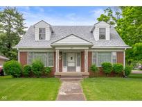 Charming brick home with dormer windows, well-kept lawn, and decorative front porch columns at 301 N Kitley Ave, Indianapolis, IN 46219