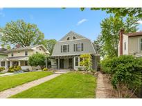 Charming two-story home featuring a covered front porch, well-maintained lawn, and mature trees under a clear blue sky at 3614 Guilford Ave, Indianapolis, IN 46205