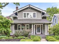 Charming two-story home with a covered front porch, lush landscaping, and inviting curb appeal at 5002 Broadway St, Indianapolis, IN 46205