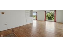 Bright living room featuring hardwood floors, built in shelving, and large windows with beautiful views at 5038 Allisonville Rd # E, Indianapolis, IN 46205