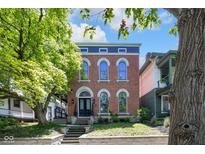 Charming brick home with arched windows and a blue accent trim under a beautiful, sunny sky at 543 Fletcher Ave, Indianapolis, IN 46203