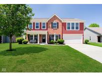 Charming two-story home with red siding, brick accents, manicured lawn, and attached two car garage at 6212 N Woods Edge Dr, McCordsville, IN 46055