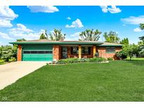 Charming brick home with a green garage door, well-maintained lawn, and manicured landscaping at 8230 Linda Leigh Ln, Indianapolis, IN 46217