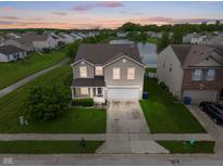 Inviting two-story home with attached two-car garage, water view, and manicured lawn at 8238 Crackling Ln, Indianapolis, IN 46259