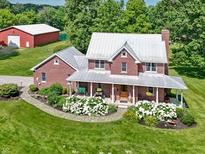 Beautiful two-story brick home featuring a metal roof, covered porch, and meticulously landscaped front yard at 19702 Centennial Rd, Sheridan, IN 46069