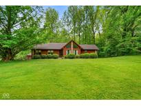 Inviting single-story home featuring a well-manicured lawn and mature trees surrounding the property at 6794 E Ann St, Camby, IN 46113