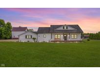 Charming white farmhouse with a large lawn, accented by a pink and purple sunset at 7895 E 175 N, Franklin, IN 46131