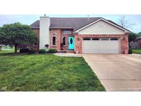 Charming brick home with a well-manicured lawn and inviting turquoise front door at 1026 Summer Way Dr, Shelbyville, IN 46176