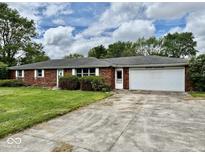 Charming brick ranch-style home featuring an attached garage, mature trees, and an expansive front yard at 1103 Canal St, Anderson, IN 46012