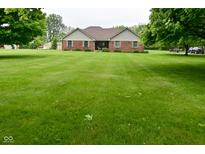 Charming brick home featuring a spacious front yard with mature trees on a partially cloudy day at 2090 W County Road 400 S, Clayton, IN 46118