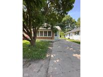 View of a single story home featuring a brick facade, green siding, and a long driveway at 3646 Creston Dr, Indianapolis, IN 46222