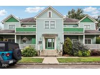 Charming two-story home with a light blue exterior, green accents, covered porches, and landscaped yard at 455 S Pine St # 4, Indianapolis, IN 46203