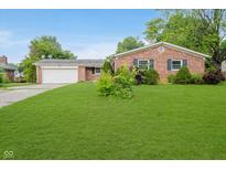 Charming single-story brick home with a spacious front lawn, garage, and manicured landscaping at 530 Westmore Dr, Indianapolis, IN 46214