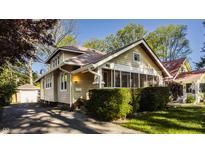Charming exterior with a screened-in porch, mature landscaping, and a detached garage behind the house at 5622 Guilford Ave, Indianapolis, IN 46220