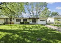 Charming single-story home with a well-maintained lawn, an attached garage, and mature shade trees in the front yard at 611 Hampton Ln, Anderson, IN 46017