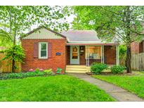 Charming brick home with a manicured front lawn, mature trees, and a cozy front porch at 752 N Leland Ave, Indianapolis, IN 46219