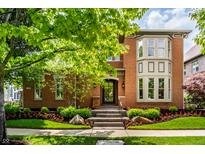 Charming brick home with manicured landscaping and inviting front entrance with stone steps and a black door at 7601 W Stonegate Dr, Zionsville, IN 46077