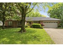 Charming brick home featuring an attached two-car garage and mature trees shading the well-manicured front lawn at 8909 Ellington Dr, Indianapolis, IN 46234