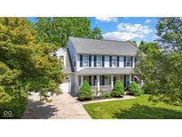 Charming two-story home with blue shutters and a welcoming front porch surrounded by mature trees at 10172 Watkins Ct, Indianapolis, IN 46234