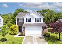 Charming two-story home with brick and white siding, lush green lawn, and a two car garage at 10876 Trailwood Dr, Fishers, IN 46038