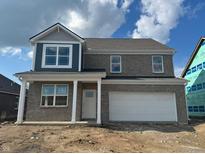 Two-story brick home featuring a covered porch, attached garage, and white-framed windows on a sunny day at 1310 Foxtail Ln, Greenwood, IN 46143