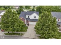 Charming two-story home featuring brick accents and a well-manicured lawn surrounded by mature trees at 14542 Baldwin Ln, Carmel, IN 46032