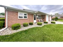 Charming brick home with well-maintained lawn and landscaping with outdoor chairs on the front porch at 2508 Pamela Ct, Anderson, IN 46012