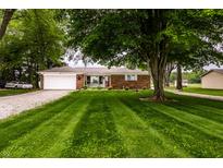Charming brick home featuring an attached garage, lush lawn and mature shade tree at 2965 E 1100 N, Pendleton, IN 46064