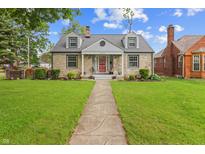 Charming stone house with a well-manicured lawn and inviting front porch and a traditional walkway to the front door at 3702 N Chester Ave, Indianapolis, IN 46218