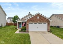 Charming brick home featuring a two-car garage, manicured lawn, and inviting entryway with American flag at 4256 Zachary Ln, Westfield, IN 46062