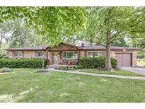 Charming brick ranch home featuring a well-manicured lawn and inviting curb appeal with a covered front entry at 5427 Heights Ave, Indianapolis, IN 46237