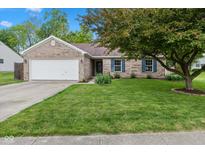 Charming brick home featuring a well-manicured lawn, mature trees, and an attached two-car garage at 560 Old Farm Rd, Danville, IN 46122