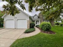 Charming home featuring a stone chimney, two-car garage, and a welcoming, landscaped front yard at 9118 Hardwood Ct, Indianapolis, IN 46250