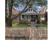 Charming two-story home with a picket fence and inviting front porch with rocking chairs at 1132 Evison St, Indianapolis, IN 46203