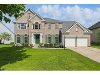 Charming two-story brick home with well-manicured lawn, attached garage, and eye-catching green shutters at 12409 Dellfield W Blvd, Carmel, IN 46033